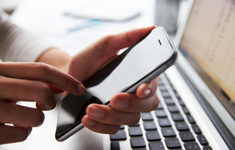 a close up of a person at laptop using mobile phone hands computer